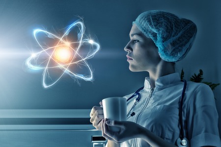 Young woman scientist looking at atom on virtual screen