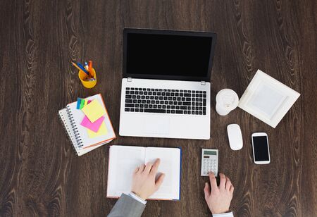 Laptop and office supplies on the wooden table as seen from aboveの写真素材