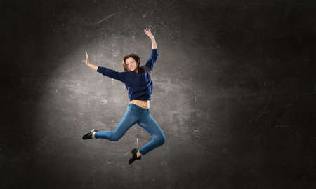 Young woman dancer in jump over dark backgroundの写真素材