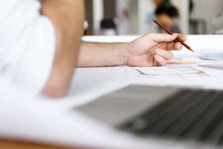Male architect with computer studying plans in office
