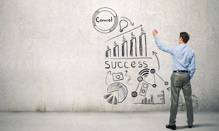 Businessman standing with back and drawing ideas on wallの写真素材