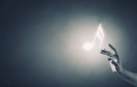 Close up of person hand touching music symbol on blue backgroundの写真素材