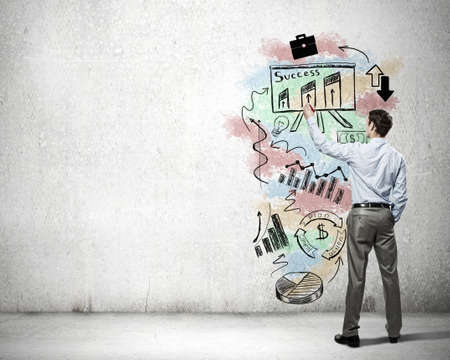 Businessman standing with back and drawing ideas on wallの写真素材