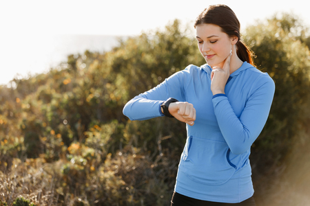 Young runner woman with heart rate monitor running on beachの写真素材