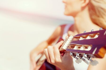 Beautiful young smiling woman playing guitar on beachの写真素材