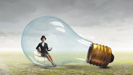 Young businesswoman trapped inside glass light bulbの写真素材