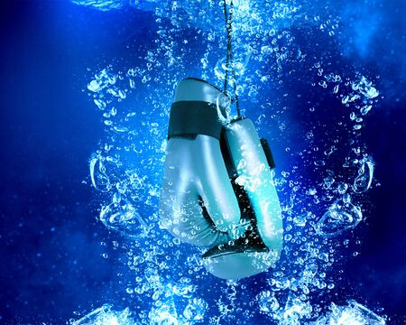 Boxing gloves sinking in clear blue waterの写真素材