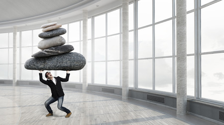 Young strong man holding huge stone above headの写真素材