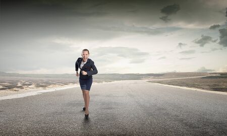 Young determined businesswoman competitor running on roadの写真素材