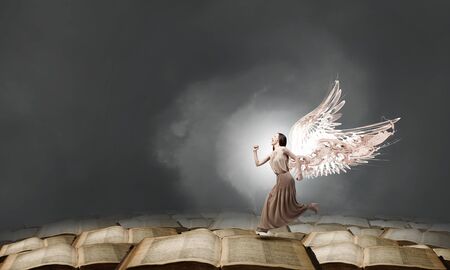 Attractive woman running with angel wings behind backの写真素材