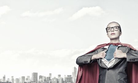 Businesswoman wearing red cape and opening her shirt like superheroの写真素材