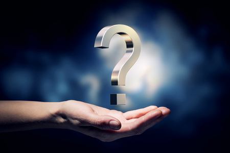 Hand holding question marks in palm on dark backgroundの写真素材