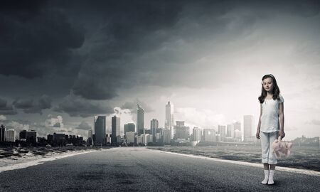 Cute girl wearing pajamas with toy bear in hand standing on roadの写真素材