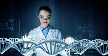 Woman scientist examining DNA molecule image at media screenの写真素材