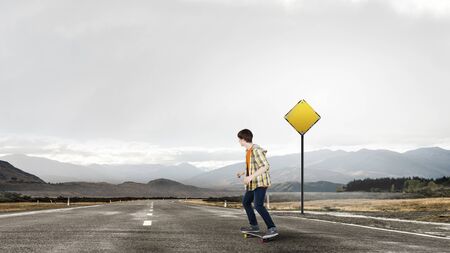 Teenager guy riding skateboard on asphalt roadの写真素材
