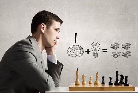 Focused young businessman and chess board on table