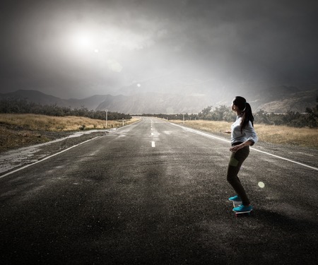 Attractive teenager girl riding skateboard on asphalt roadの写真素材