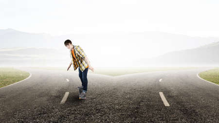 Teenager guy riding skateboard on asphalt roadの写真素材