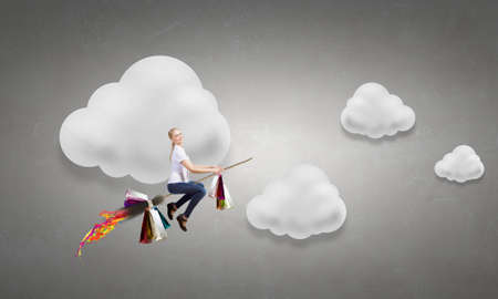 Young attractive girl in casual flying on broomの写真素材