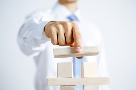 Close up of businessman building pyramid with wooden cubesの写真素材