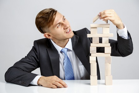 Young businessman making pyramid with empty wooden cubesの写真素材