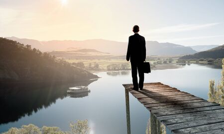 Businessman standing on dock of lake and enjoying silenceの写真素材