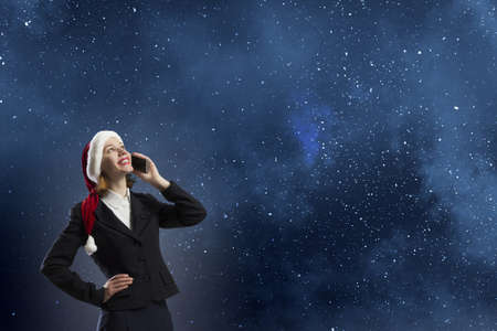 Young businesswoman in Santa hat talking on mobile phoneの写真素材