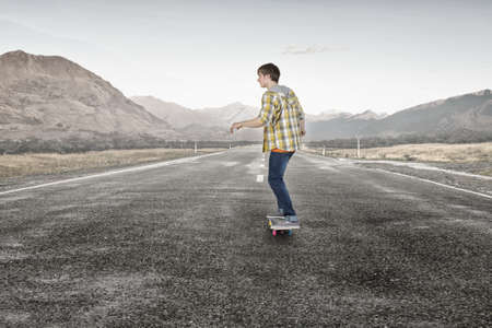 Teenager guy riding skateboard on asphalt roadの写真素材