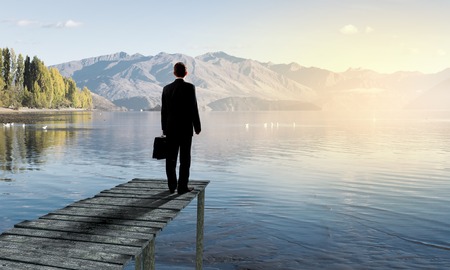 Businessman standing on dock of lake and enjoying silenceの写真素材