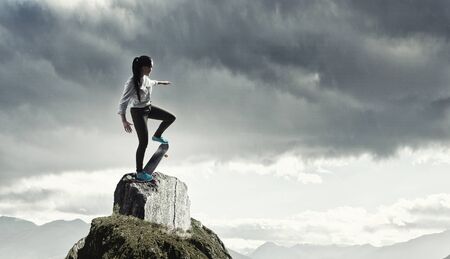Attractive teenager girl riding skateboard on rock topの写真素材