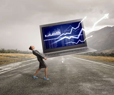 Elegant businesswoman carrying huge laptop in hands