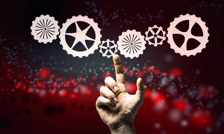 Hand of businessman touching cogwheel mechanism on color backgroundの写真素材