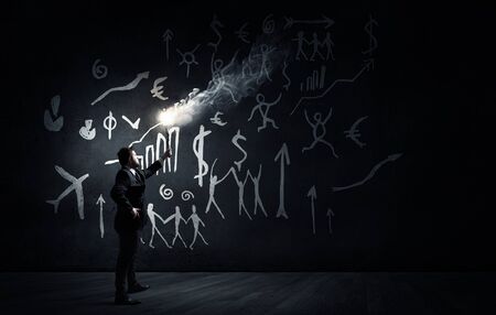 Young businessman in darkness holding burning torch in handの写真素材