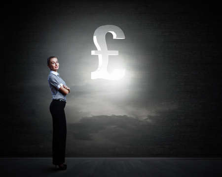 Attractive businesswoman and pound sign on dark backgroundの写真素材