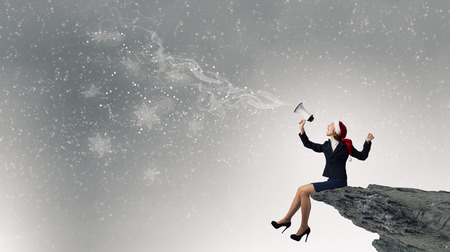 Woman in suit and Santa hat shouting into megaphoneの写真素材