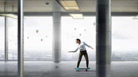 Attractive teenager girl riding skateboard in interiorの写真素材