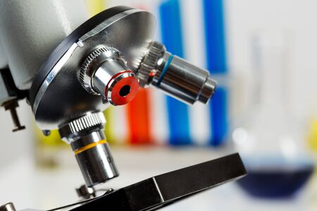 Glass tubes with color liquids and microscope in science laboratory