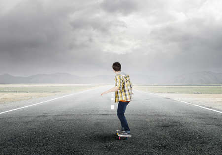 Teenager guy riding skateboard on asphalt roadの写真素材