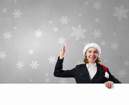 Woman in Santa hat with blank banner pointing with. Place for your textの写真素材