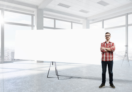 Young man in casual in office interior near blank white bannerの写真素材