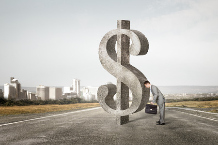 Businessman leaning with forehead on dollar big signの写真素材