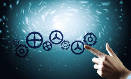 Hand of businessman touching cogwheel mechanism on color backgroundの写真素材