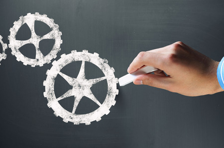 Businessman hand drawing with chalk gears mechanism as teamwork conceptの写真素材