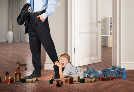 Close up of legs of man going to work and his son asking him not to goの写真素材