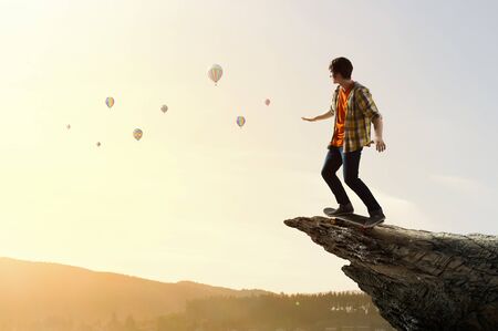 Active teenager guy riding skateboard on rock topの写真素材