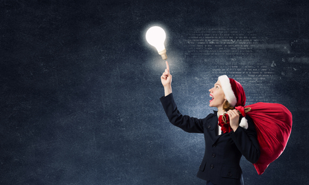 Santa woman with red bag on back pointing up with fingerの写真素材