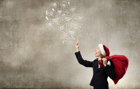 Santa woman with red bag on back pointing up with fingerの写真素材