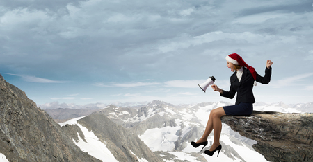 Woman in suit and Santa hat shouting into megaphoneの写真素材
