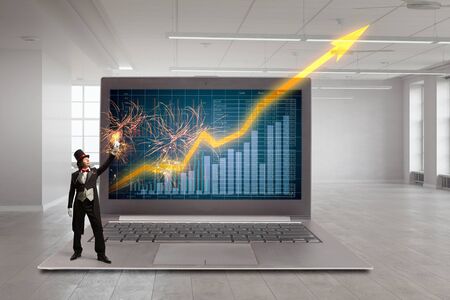 Magician and big laptop with infographs on screenの写真素材