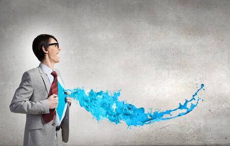 Young businessman acting like super hero and tearing his shirt offの写真素材